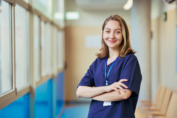 Young confident nurse smiling in hospital corridor