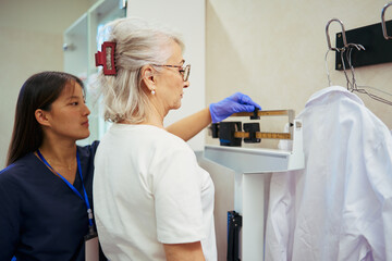 Medical staff performing weight measurement on patient in hospital room
