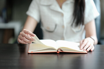 Close-up of a woman reading a book on the table.