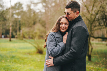 Fototapeta premium Couple enjoying a warm embrace in a serene park during a sunny autumn day