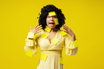 Shocked businesswoman covered with yellow sticky notes screaming on yellow background