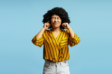Young woman covering ears ignoring annoying loud noise, plugging ears with fingers