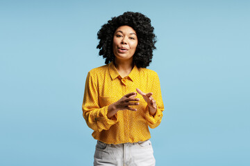 Young woman explaining something using hand gestures on blue background