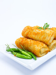 A plate of crispy golden vegetable risol served with green chili peppers and parsley garnish. isolated on white background. risol isolated