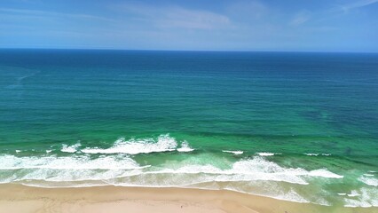 The Serene Beach Waves Softly and Gently Crash Against the Lovely Clear Blue Sky Above You