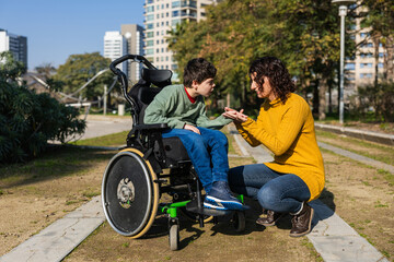 Mother playing with son in wheelchair at park