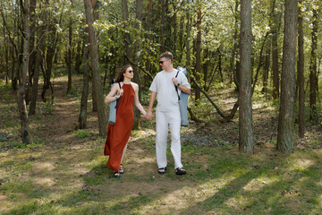 Fototapeta premium Young couple enjoying a spring walk in a blooming forest holding hands together