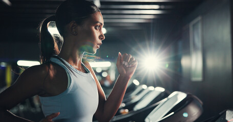 Workout, girl and running on treadmill in gym at night for fitness, training and burning calories. Flare, late exercise and athlete with breathing for intense cardio, endurance challenge and wellness © peopleimages.com