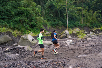 Fototapeta premium Asian Trail Runners Jogging on Rocky Path in Forested Mountain Area