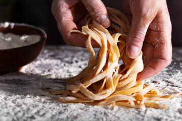 Caucasian female hands holding raw fettuccine noodles after drying