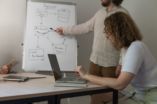 Three software developers brainstorming in a modern office. Team coding session with laptops showing code, planning web development and design. Tech startup environment and teamwork