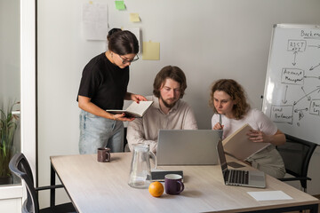 Three software developers brainstorming in a modern office. Team coding session with laptops...