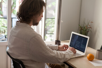 Three software developers brainstorming in a modern office. Team coding session with laptops...