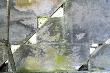 old cement wall with triangular holes covered with moss