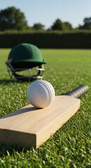 Cricket bat with white ball on green grass field, protective helmet in background. Summer daylight game preparation scene, outdoor sports equipment ready for match