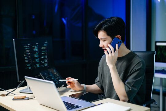 Asian software developer working late with code on screens, tablet, and phone. Concept of programming, tech lifestyle,