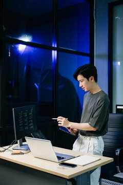 Young male programmer working with tablet and screen displaying code. Modern tech office setup, great for software, coding, IT..