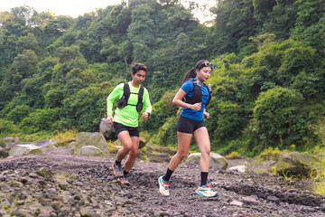 Asian Trail Runners Jogging on Rocky Path in Forested Mountain Area