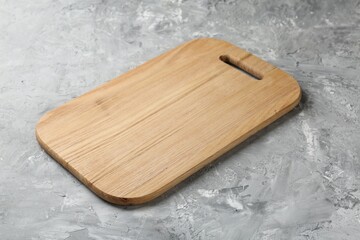 One wooden serving board on light grey textured table, closeup. Space for text