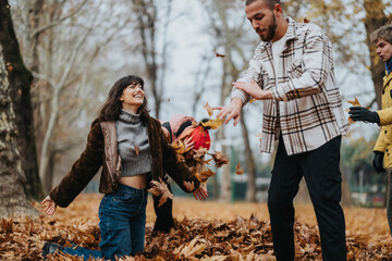 A joyous group of friends enjoying their time outdoors during autumn, playing with fallen leaves...