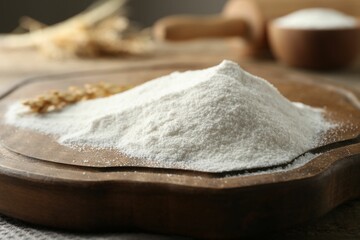 Flour and wheat spikelet on wooden board, closeup