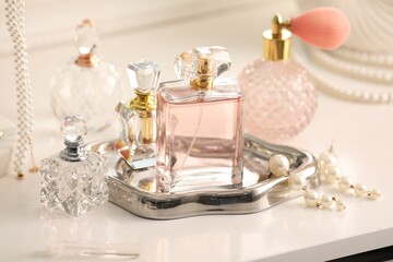 Bottles of different perfumes and accessories on dressing table indoors, closeup
