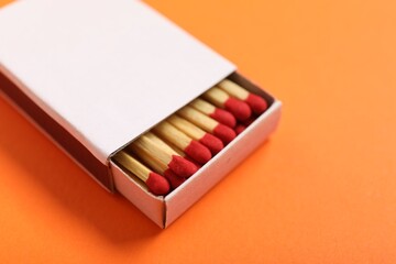 Matches in box on orange background, closeup. Mockup for design
