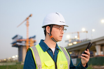 asian male engineer using smart phone in construction site