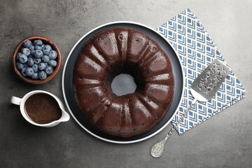 Tasty chocolate bundt cake, blueberries and server on grey table, flat lay