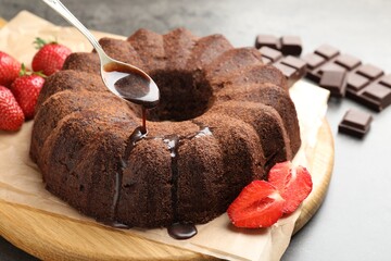 Pouring glaze onto chocolate bundt cake at table, closeup