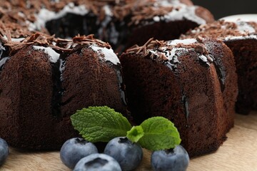 Delicious bundt cake with blueberries, mint and chocolate shavings on wooden table, closeup