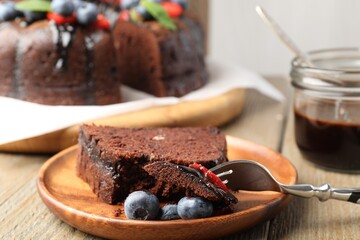 Piece of delicious chocolate bundt cake with blueberries on wooden table, closeup