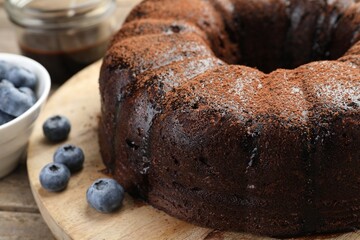 Delicious chocolate bundt cake with blueberries on wooden table, closeup