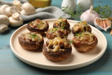 Delicious stuffed mushrooms with melted cheese and thyme on light blue wooden table, closeup