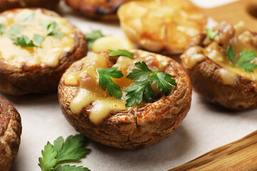 Delicious stuffed mushrooms with melted cheese and parsley on wooden table, closeup