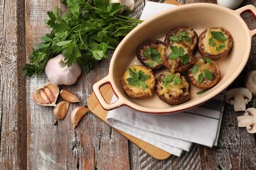 Delicious stuffed mushrooms in baking dish and products on color wooden table, flat lay
