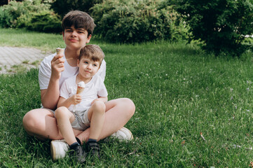 Teenage brother and young sibling enjoying ice cream together on a sunny summer day