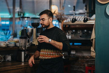 A barista stands in a warmly lit cafe, holding a cup. The ambiance is welcoming, featuring a stylish design with various decorative elements and a focus on coffee preparation equipment.