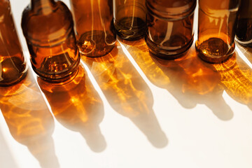 Bottom view of amber glass bottles casting warm glowing shadows and reflections on white surface