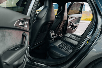 Sports car interior. Black premium leather, bucket seats, steering wheel, buttons, console with gears and widescreen. Luxury car interior design. Marketing, advertising or press articles.