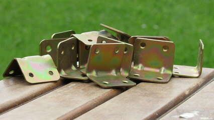Various metal brackets arranged on a wooden surface with a green grass background