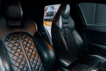 Sports car interior. Black premium leather, bucket seats, steering wheel, buttons, console with...