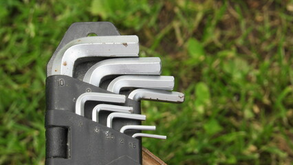 Various metal hex keys resting on a wooden table in a garden setting during daylight hours