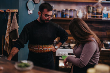 A man and woman engaged in friendly food preparation in a warmly lit kitchen. The utensils and surroundings create an inviting and homely atmosphere perfect for cooking and socializing.