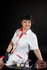 Teacher in a lab coat on a black background with a set of chemical compounds and various glass test...