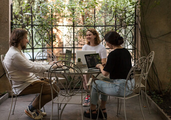 Three software developers brainstorming in a modern office. Team coding session with laptops...