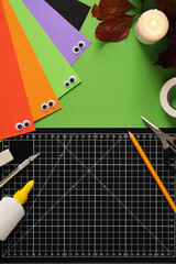 Supplies for Halloween-themed paper crafts. Pencil, glue, eraser, knife, scissors, and colored...