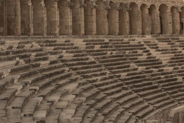 Part of the amphitheater with a stone staircase and a wall in the background. The wall has arches