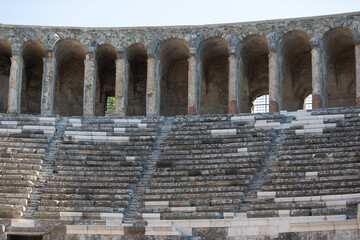 Ancient amphitheater with stone seating and archways in a historic location