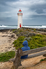 Person Viewing Griffiths Island Lighthouse from Wooden Bench on Coastal Path
